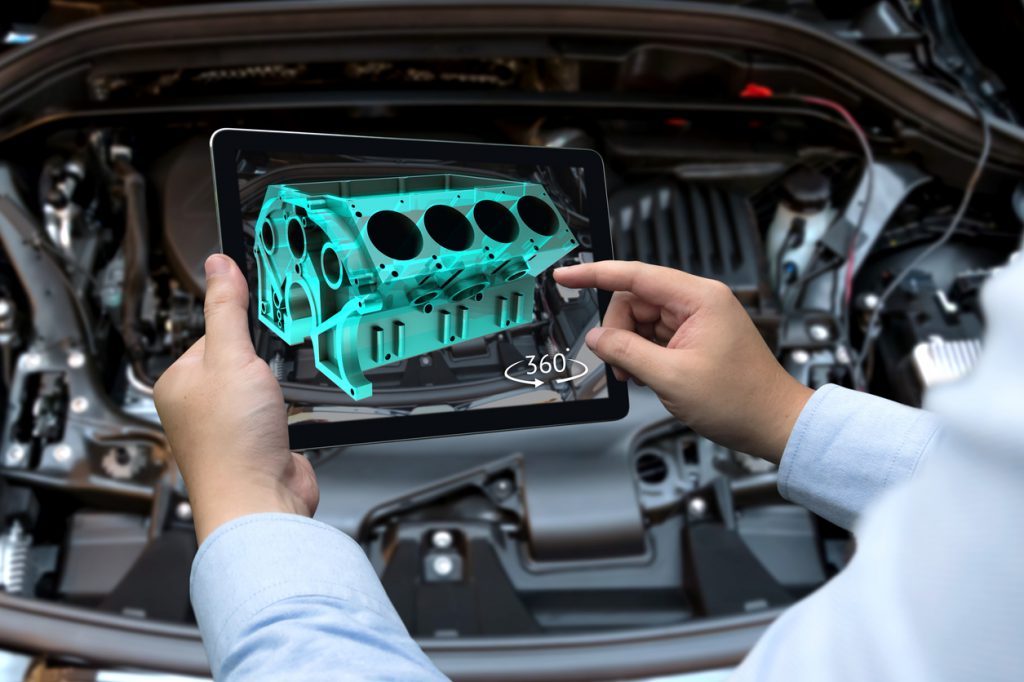 Augmented reality technology and engineering marketing concept. Hand holding tablet with AR service application to rotate 3d rendering of energy block 360 degrees with blur car engine room background
