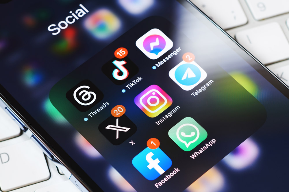 A close up of a phone screen displaying several different social media for business apps: Threads, TikTok, X, Instagram, Facebook and others.